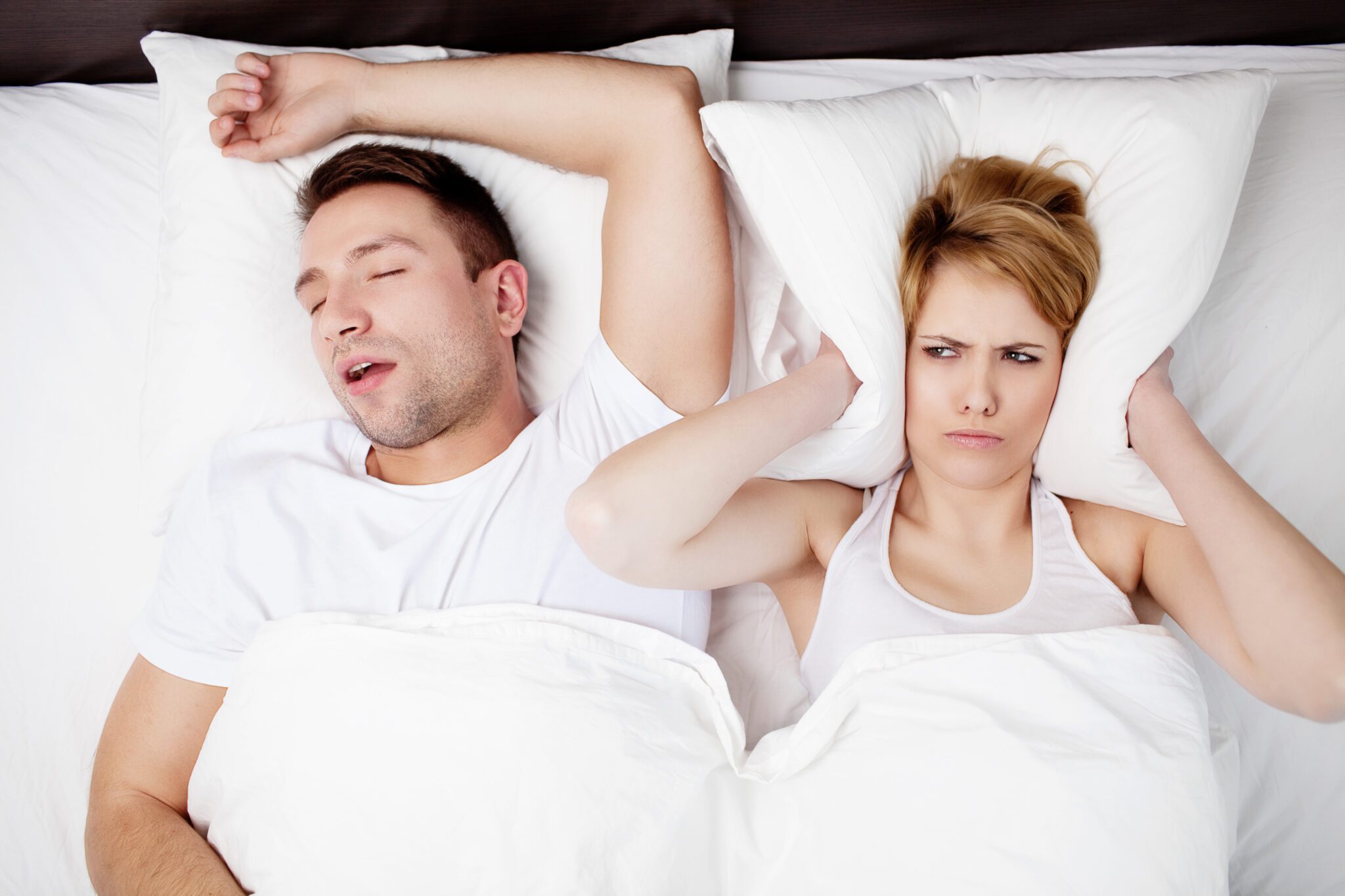 Snoring man problem. couple in bed with man snoring - Ideal Image Dentistry