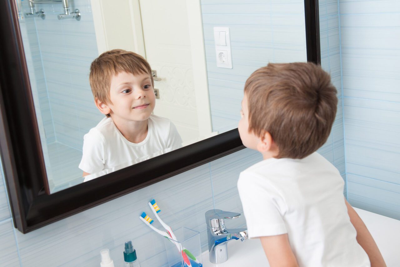 little boy looking in mirror - Ideal Image Dentistry